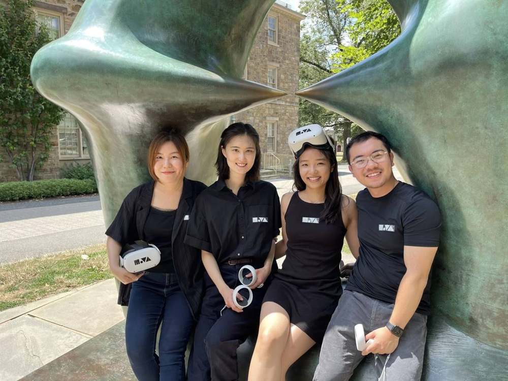 The MoVA team, four people in black MoVA shirts holding VR headsets and controllers.