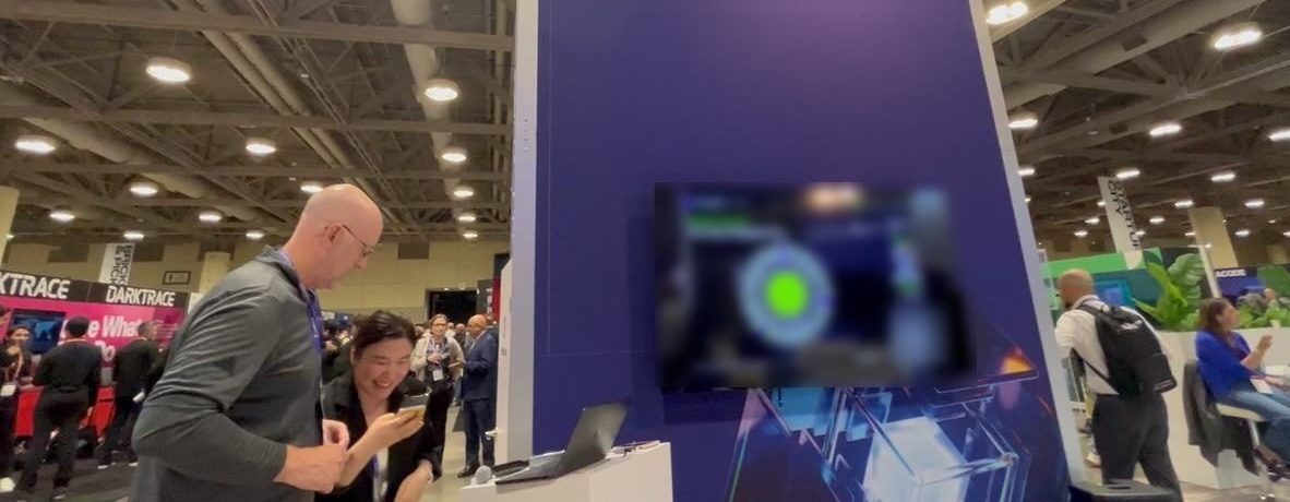 Attendees checking their phones in front of the live Oura Ring draw wheel on the booth screen.